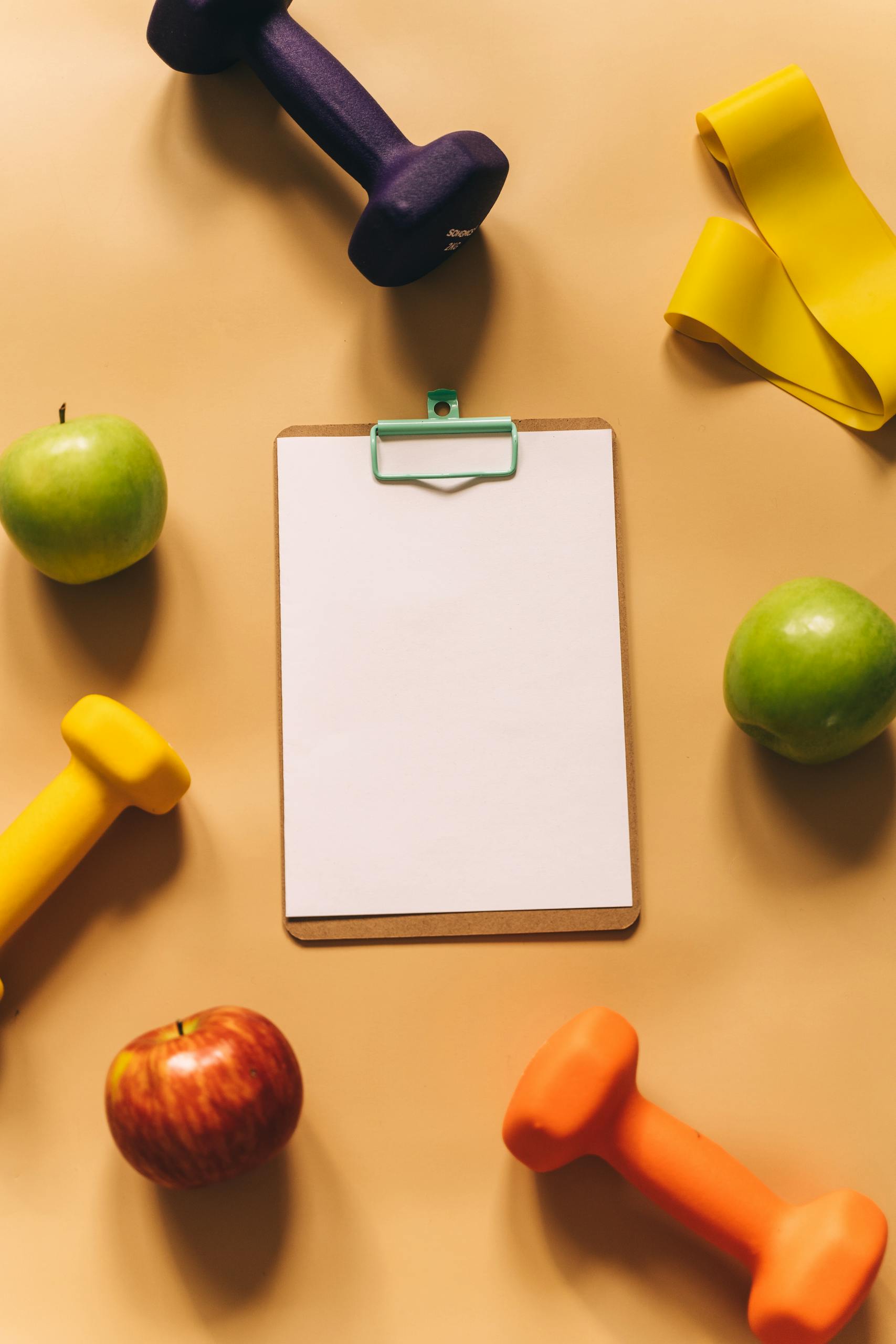 Stylish flat lay showcasing fitness equipment and apples on a beige background for health inspiration.